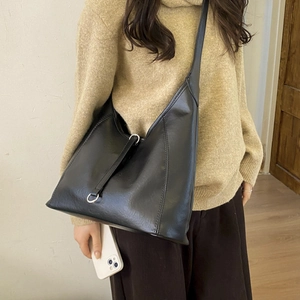 Detail of a black large-capacity tote bag with silver metal ring and soft leather texture