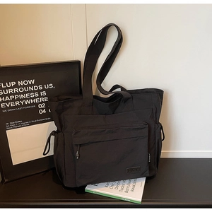 Detail of black nylon tote bag with front zipper pocket and drawstring side compartments