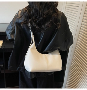 Detailed texture of off-white lychee pattern hobo bag worn over a black leather jacket