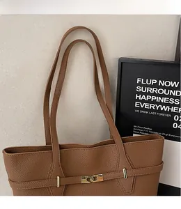 Detail of smooth leather shoulder straps and golden metal buckle on a brown tote bag