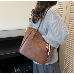 Detail of a brown PU leather tote bag with contrast stitching and fashion label