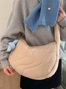 Quilted crescent crossbody bag in beige with wave pattern and blue knot charm