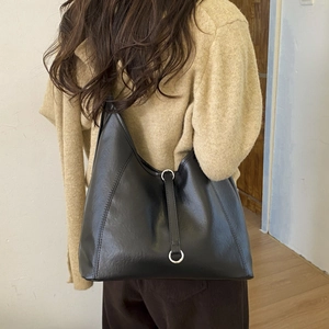 Detail of minimalist black matte tote bag with silver ring hardware and leather strap