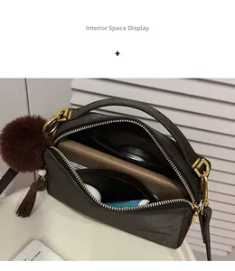 Détails de l'intérieur du sac à bandoulière marron foncé avec deux compartiments et pompon