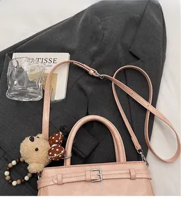 Dettaglio borsa in pelle PU rosa con ciondolo a forma di orsetto e tracolla regolabile