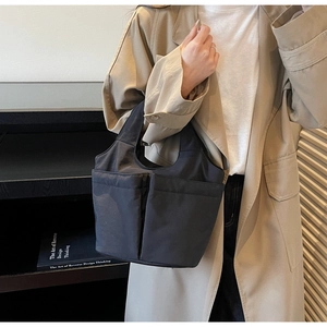 Close-up of black multi-pocket nylon tote bag styled in a minimalist aesthetic