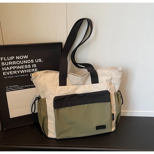 Detail of color-block tote bag with olive green nylon fabric and black zipper pocket