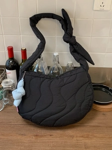 Quilted black puffer bag with knotted strap and wave stitching for winter style