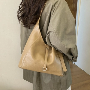 Minimalist beige leather tote bag featuring a decorative metal ring buckle on the side