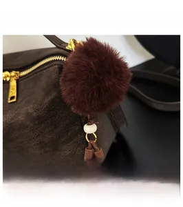 Détail d'un sac en cuir marron avec pompon en peluche, perles et accessoires à franges