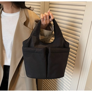 Detail of black nylon tote bag with dual front pockets and integrated wide handle