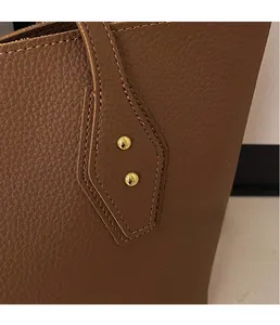 Detailed close-up of brown litchi pattern leather tote with gold rivet hardware studs