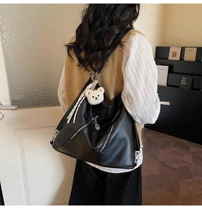 Détail du sac fourre-tout noir en similicuir avec zip latéral et porte-clé ours blanc