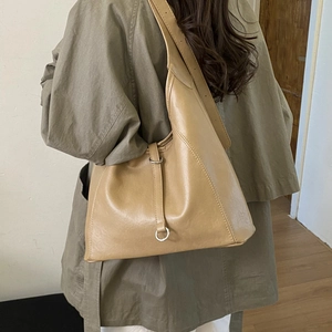Detail view of khaki leather tote bag with wide shoulder strap and silver metal ring buckle