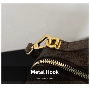 Détail du crochet en métal doré et du cuir marron texturé sur un sac à main chic