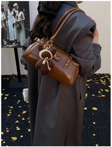 Detail of vintage brown leather shoulder bag with gold rivets and cute bear charm decoration