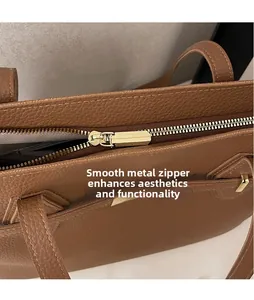 Macro view of gold metal zipper pull and lychee texture on brown leather tote