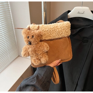 Detalle de bolso de ante marrón con ribete de forro polar blanco y tierno oso de peluche
