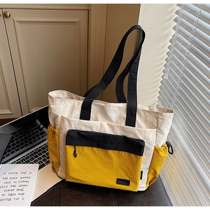 Detail of canvas tote bag with contrast pockets, logo patch and organized compartments