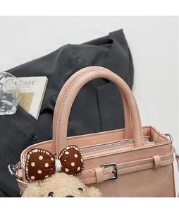 Dettaglio borsa a mano rosa con manici circolari e ciondolo orsetto di peluche carino