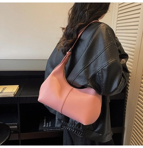 Pink lychee grain leather crescent bag shown from side angle on a shoulder