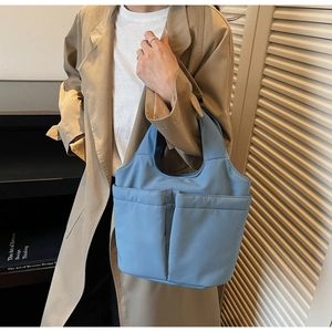 Close-up of blue soft nylon tote bag showing dual front pockets and durable stitching