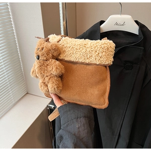 Detalle del bolso bandolera de ante marrón con ribete de lana de cordero y amuleto de oso