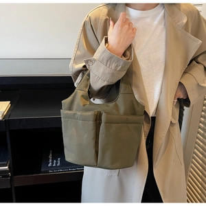 Detail of olive green nylon tote bag featuring functional front pockets and sturdy handles