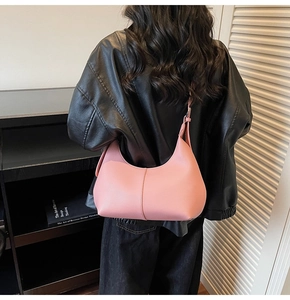Pink lychee grain leather hobo bag worn by model with adjustable shoulder strap