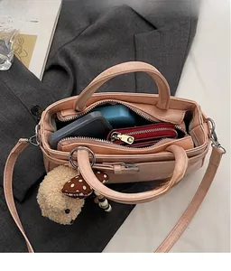 Dettaglio dell'ampio interno della borsa a secchiello beige con ciondolo peluche