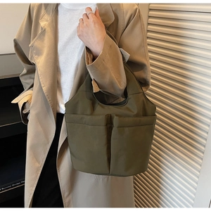 Detail of water-resistant nylon tote bag with front pockets in dark olive green