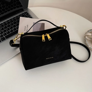 Détail d'un sac bandoulière noir mat avec fermetures éclair dorées sur un bureau