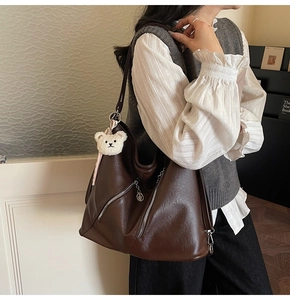 Détail du sac cabas vintage en cuir marron avec fermeture éclair et charm ours en peluche
