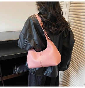 Close-up of pink crescent shoulder bag with pebbled leather texture and adjustable strap