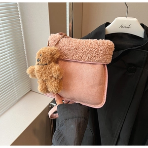 Detalle del bolso bandolera de lana de cordero rosa con textura de ante y oso de peluche