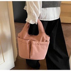 Detail of a dusty pink nylon tote bag with functional front pockets and a wide handle