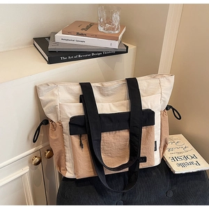 Detail of color-block tote bag with drawstring side pocket and textured nylon fabric