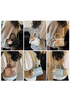 Détail de sacs à bandoulière de luxe en quatre couleurs avec un charm d'ours sur un mannequin