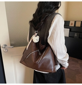 Détail d'un sac cabas en similicuir marron avec poches zippées et petit ours en peluche