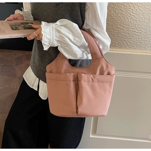 Detail shot of dusty rose nylon tote bag with functional front pockets and textured fabric