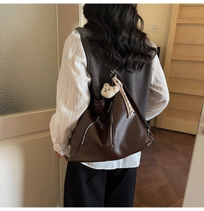 Détail du sac cabas en cuir marron avec double fermeture éclair et charm d'ours peluche