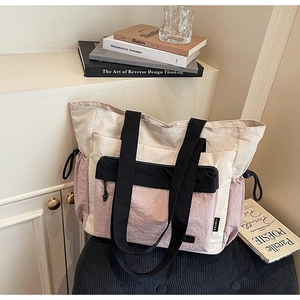 Detail view of large tote bag featuring tricolor paneling and side drawstring pockets