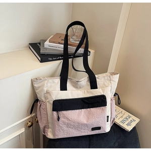 Detail of color-block travel tote bag with drawstring pockets on a cozy grey velvet chair
