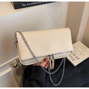 Close-up of beige pebble leather handbag featuring silver chain strap and dual zippers