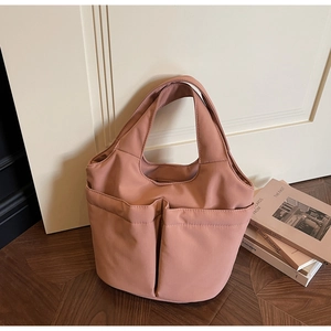 Close-up of large capacity tote bag with dual front pockets on vintage wood floor