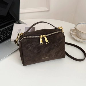 Détail du sac à main vintage en cuir marron texturé avec quincaillerie dorée et logo