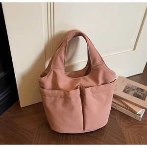 Detail of rose pink nylon tote bag with multi-pocket design on a wooden background
