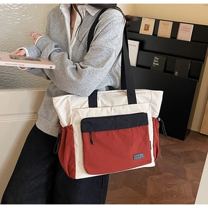 Detail of color-block tote bag with drawstring side pockets and a zipper front compartment