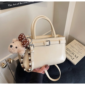 Détail du sac seau blanc crème avec breloque ours en peluche et lanière en perles décorative
