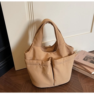 Detail showing the khaki multi-pocket tote bag with precise stitching and fabric texture